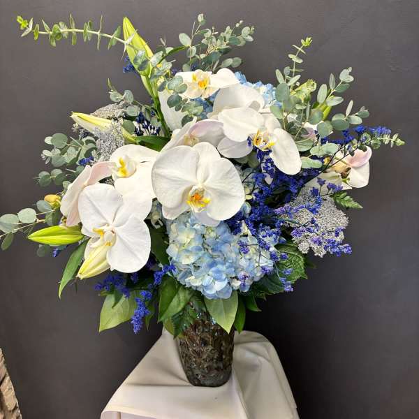 White orchids and blue hydrangeas in a glass vase