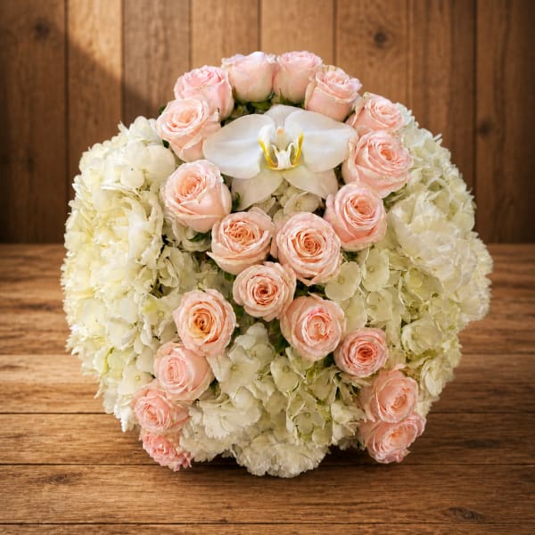 Round bouquet of pale pink roses and white hydrangeas with a white orchid center