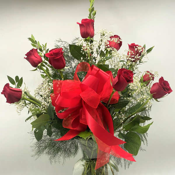 Red roses in a clear glass vase with a large red bow