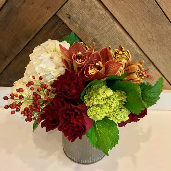 Mixed bouquet in a metal container with white, red, and green blooms