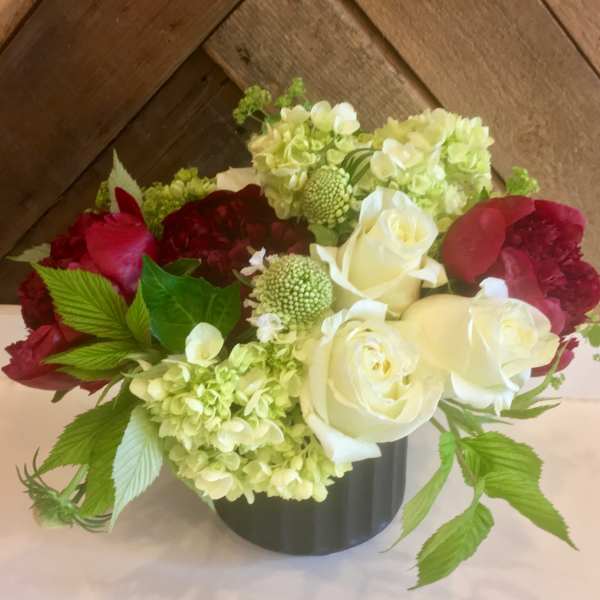 Bouquet of white and red roses with pale green hydrangeas in a black vase