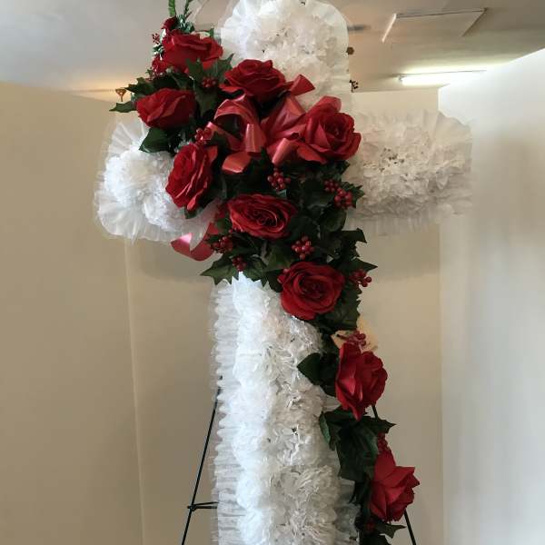 Standing cross covered with red roses and white ruffled flowers