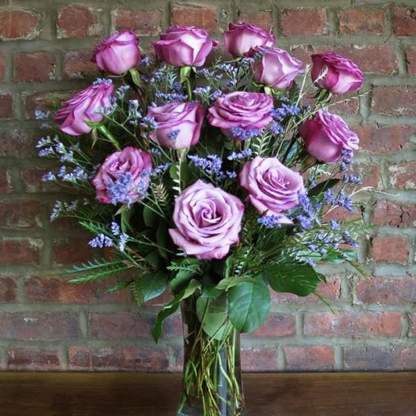 Bouquet of lavender roses with purple filler in a glass vase