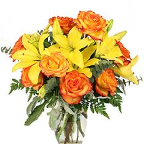 Bouquet of orange roses and yellow lilies in a clear glass vase