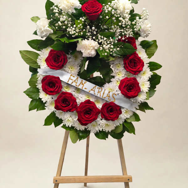 Red roses and white flowers arranged on a standing easel with a ribbon