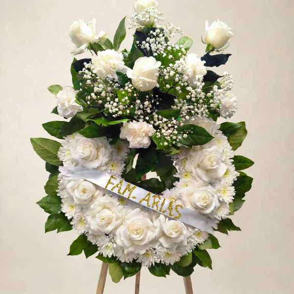 White rose and chrysanthemum wreath on an easel with a ribbon