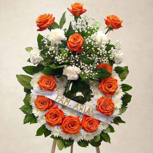 Orange roses and white flowers arranged on a standing easel wreath