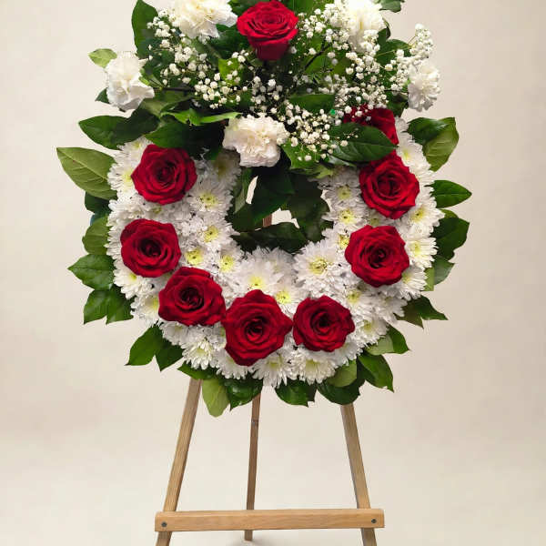 Red roses and white flowers arranged on a standing easel wreath