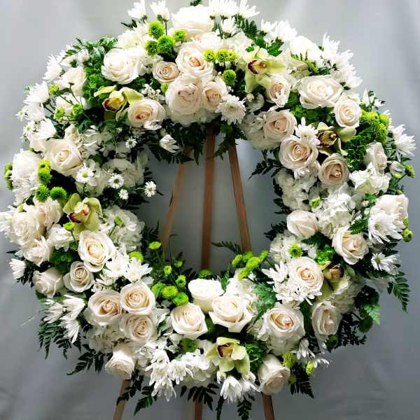 Large white floral wreath on a wooden stand