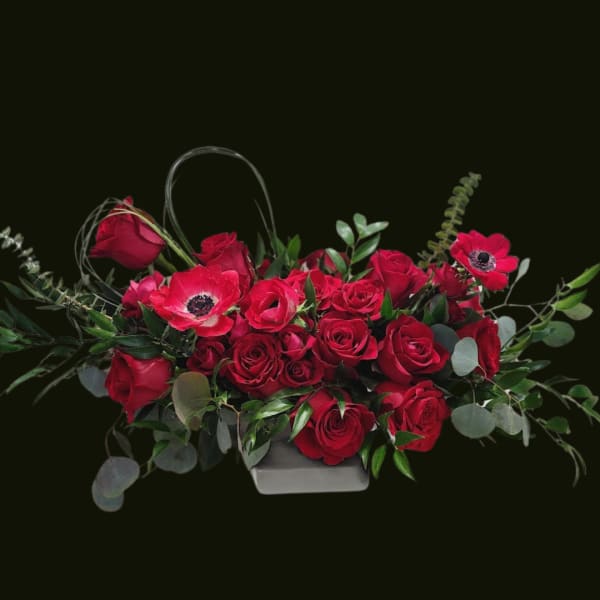 Red roses and red anemones in a low rectangular container
