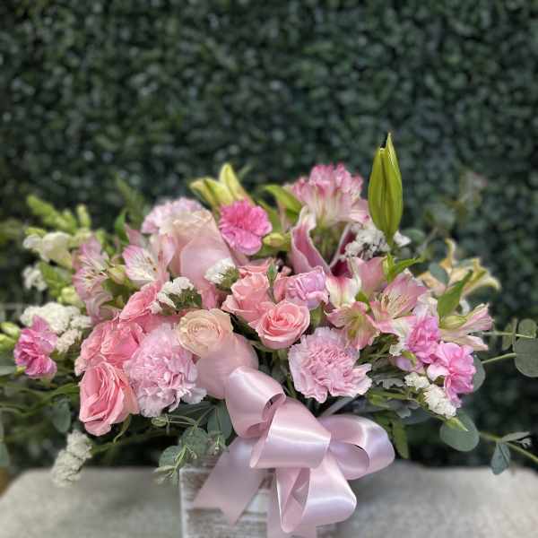 Pink bouquet of roses, carnations, and lilies in a box with a ribbon