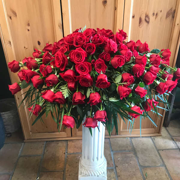Large arrangement of red roses in a white pedestal vase