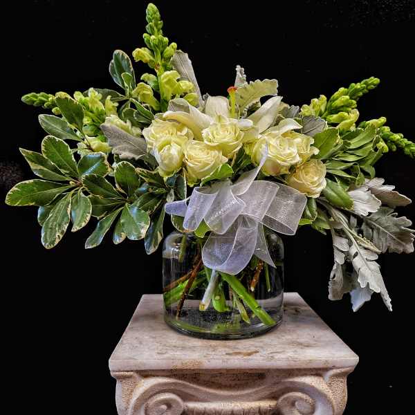 White roses in a glass vase with a sheer ribbon
