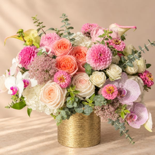 Pink and white floral arrangement in a gold vase