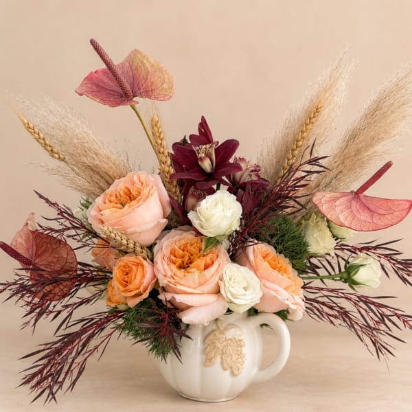 Peach and white roses in a white ceramic mug with dried grasses