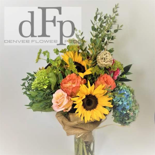 Bouquet with sunflowers, roses, hydrangea, and greenery in a glass vase