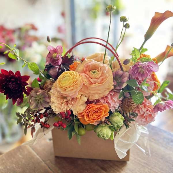 Mixed floral arrangement in a square box with peach, pink, orange, and burgundy blooms