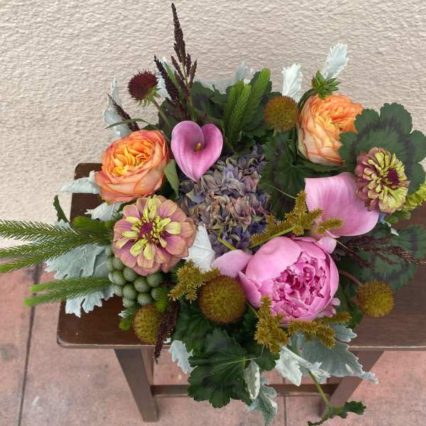 Mixed bouquet with pink peonies, orange roses, calla lilies, and zinnias