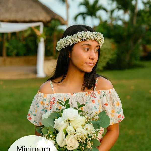 Young woman outdoors holding a white rose bouquet and wearing a white flower crown