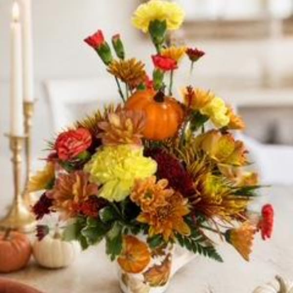 Autumn floral arrangement with pumpkins in a vase