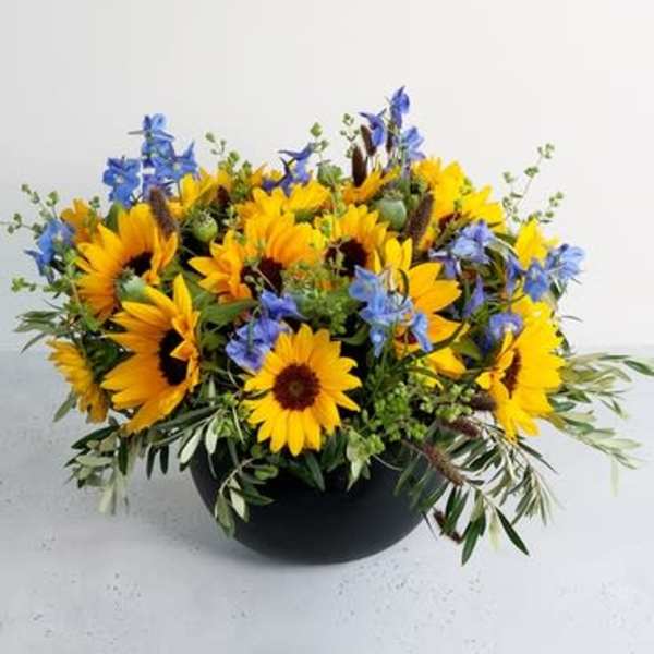 Yellow sunflowers and blue flowers in a black bowl vase