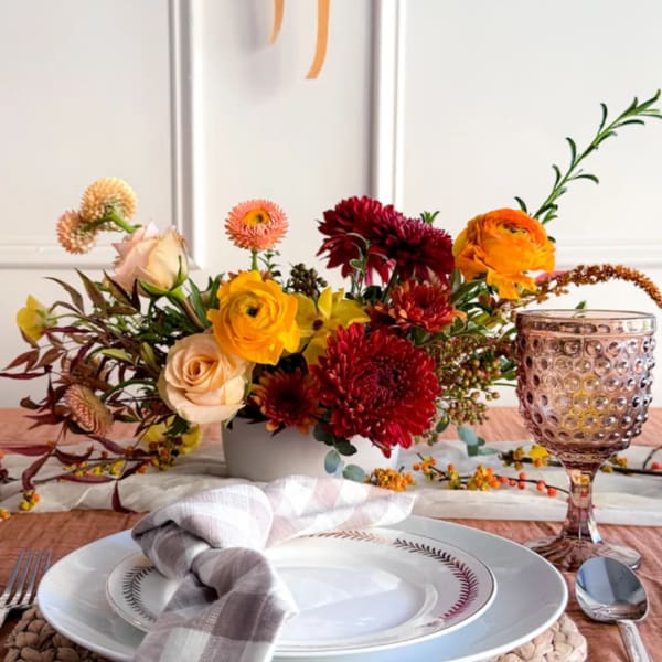 Mixed floral centerpiece in a low white vase with roses and chrysanthemums