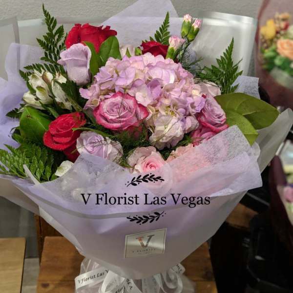 Bouquet of pink and red roses with hydrangea in lavender wrap