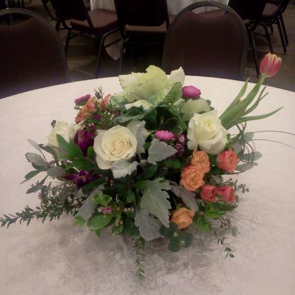 Low floral centerpiece with roses and tulips on a round table