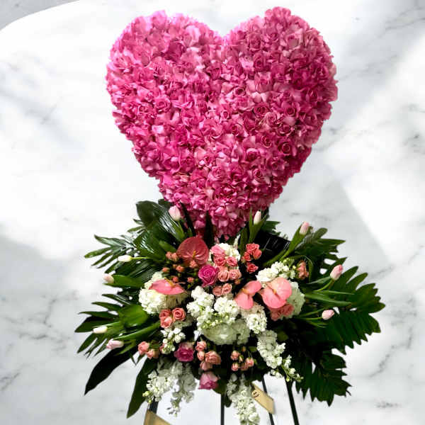 Heart-shaped pink floral tribute above a mixed flower spray