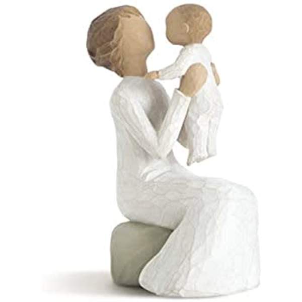 Two carved figures in white dresses seated together on a block