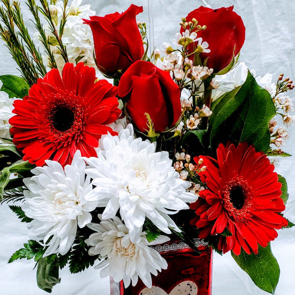 Red roses and gerbera daisies in a red heart vase