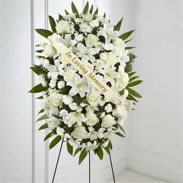 White sympathy standing spray with a ribbon on an easel