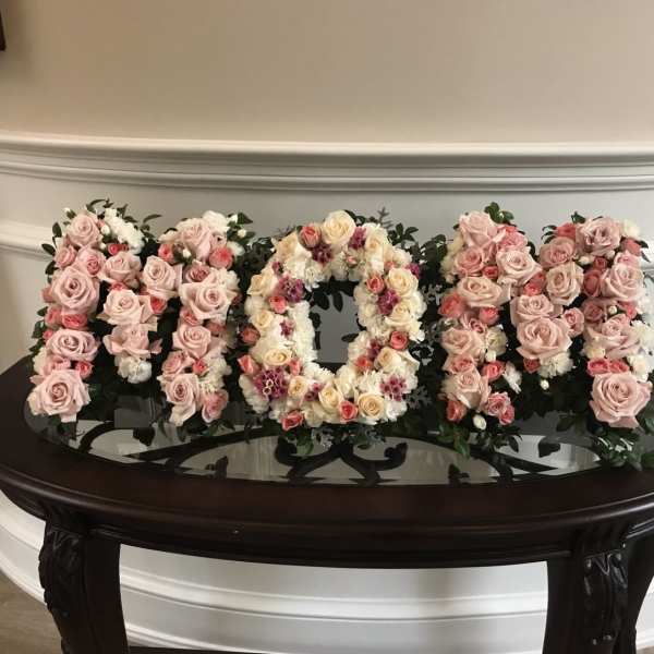 Floral arrangement spelling "MOM" with pink and cream roses