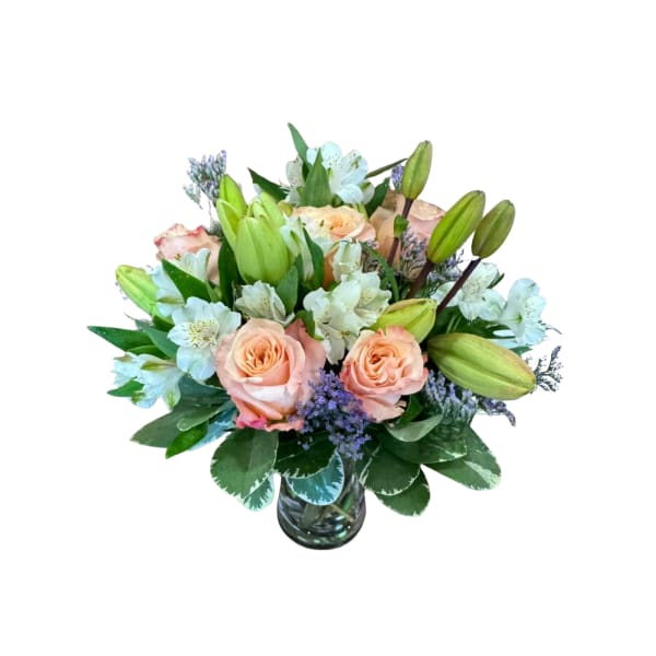 Peach roses and pale lilies in a glass vase