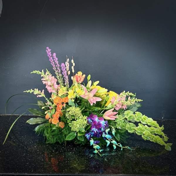 Low floral arrangement with pink, yellow, orange, and purple blooms