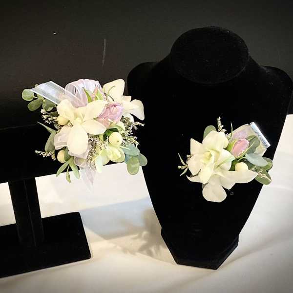 Pair of floral corsages with white and pale pink flowers on black display stands