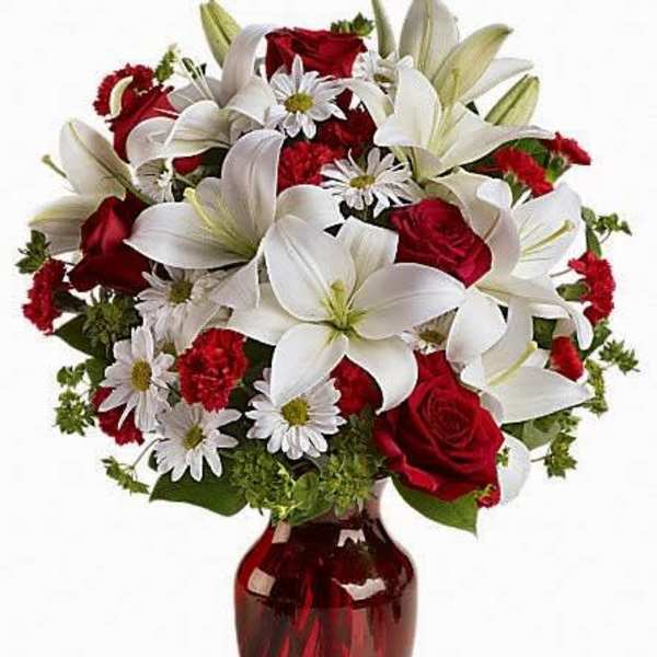 Bouquet of red roses and white lilies in a red glass vase