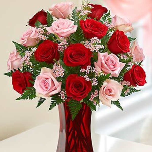 Red and pink roses arranged in a red glass vase