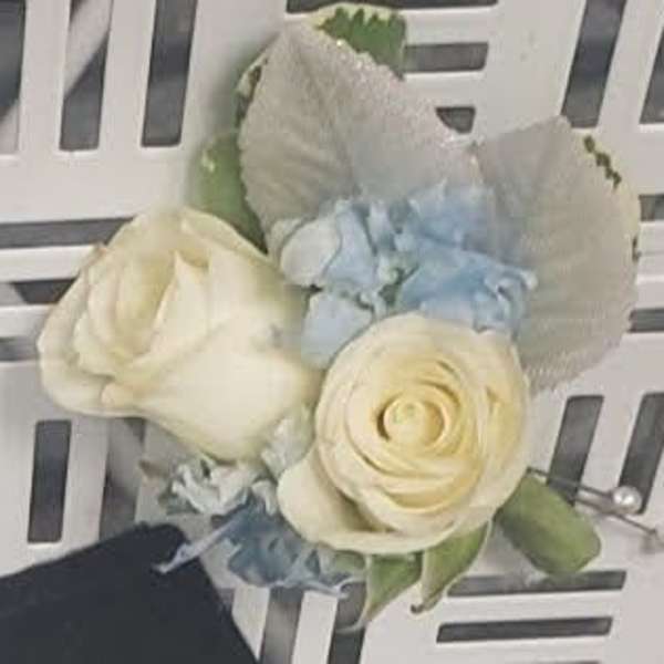 Cream rose boutonniere with pale blue flowers and white shell accents
