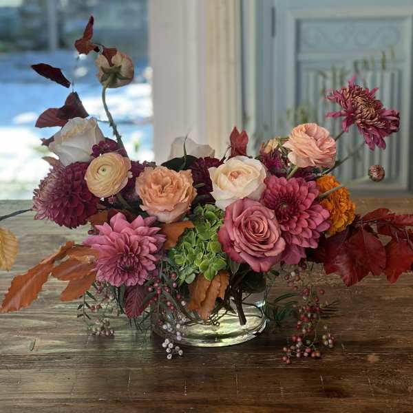 Mixed pink and peach flower arrangement in a clear glass bowl