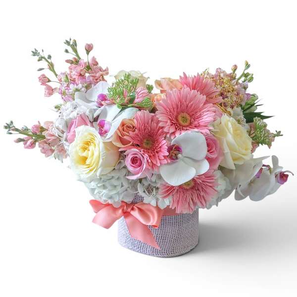 Pink and white mixed flower arrangement in a textured round box with a ribbon