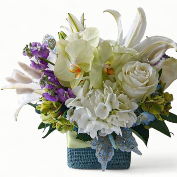 Compact arrangement of white lilies, orchids, hydrangeas, and roses in a blue square vase