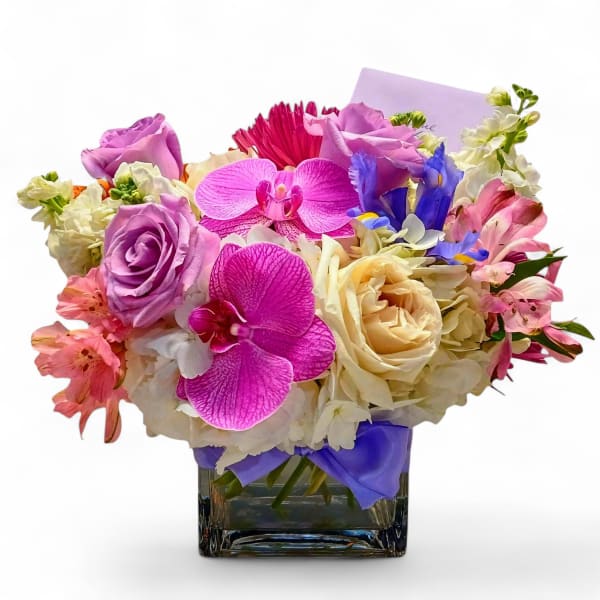 Mixed bouquet of pink, purple, and white flowers in a glass vase