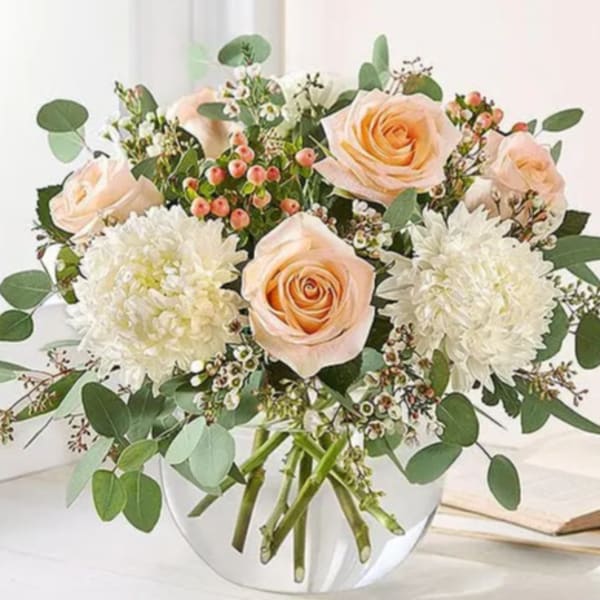 Peach roses and white chrysanthemums in a clear glass vase