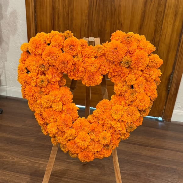 Heart-shaped marigold floral wreath on a wooden stand