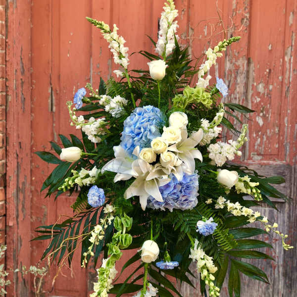 Tall floral spray with white lilies, blue hydrangeas, and white roses