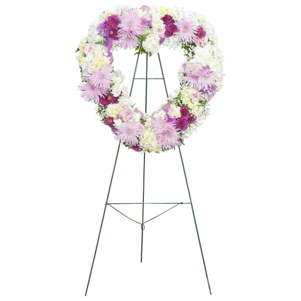 Heart-shaped standing wreath with white, lavender, and purple flowers on a metal easel