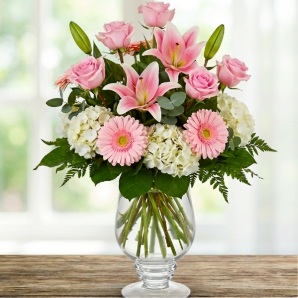 Pink roses, lilies, gerbera daisies, and white hydrangeas in a glass vase