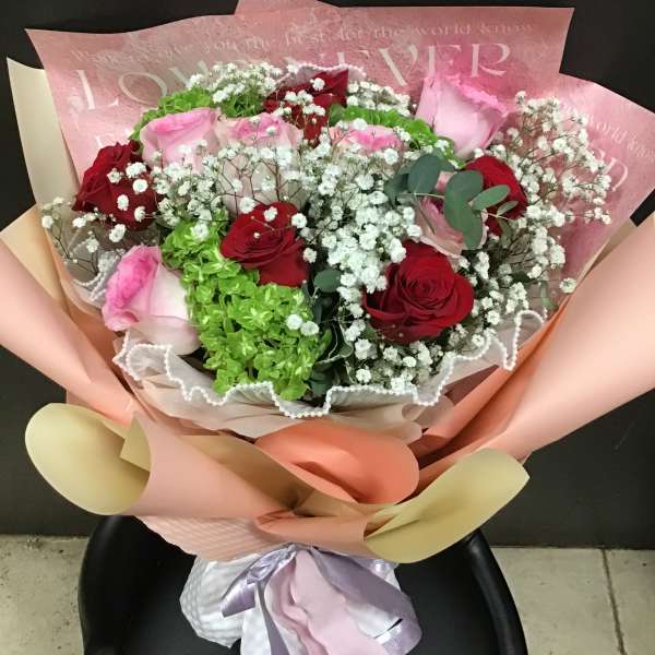 Bouquet of red and pink roses with white baby's breath in pastel wrapping