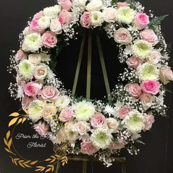 Pink and white rose wreath with white chrysanthemums on a stand